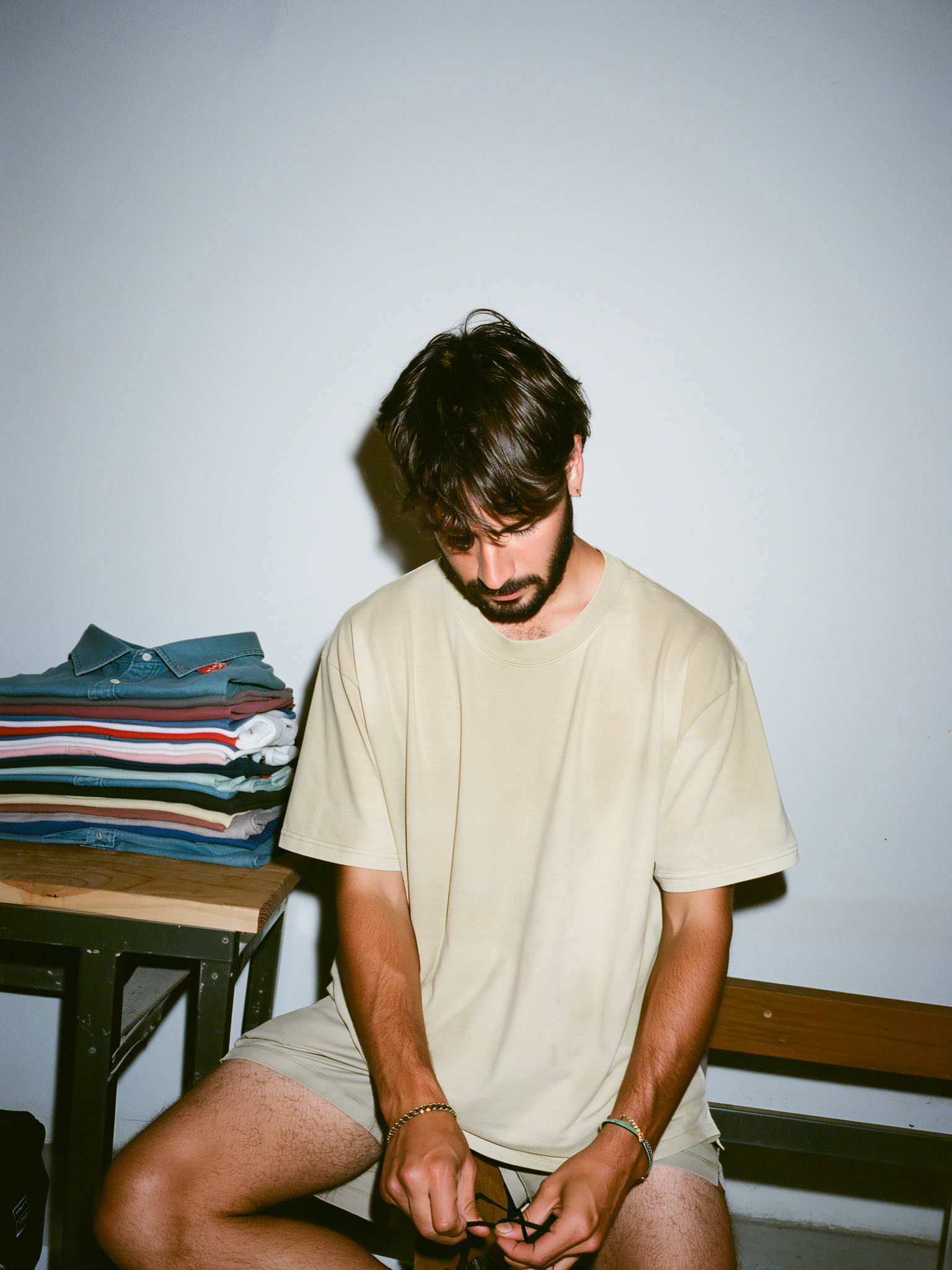Model in an oat heavyweight tee at a folding table in a print studio