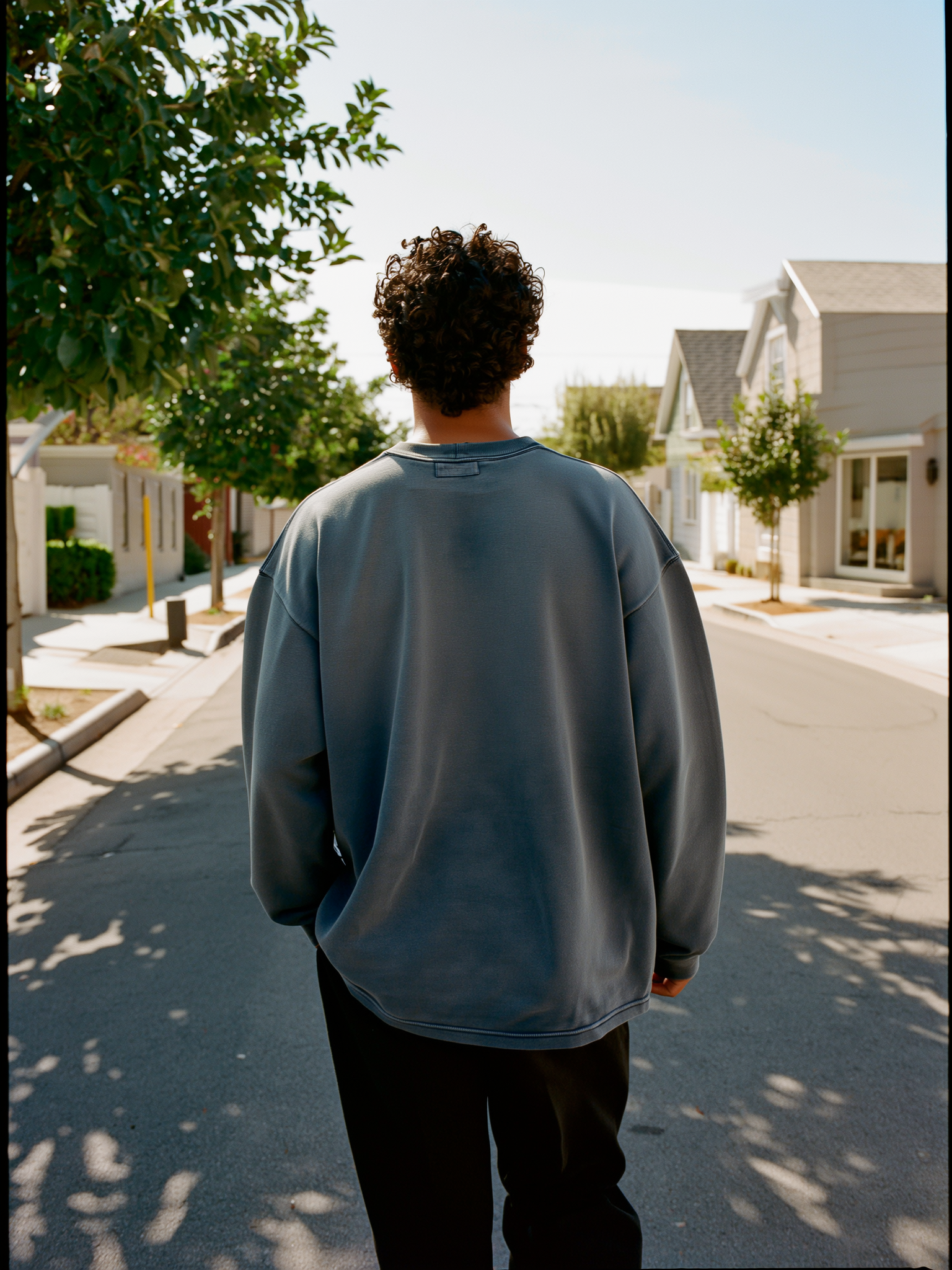 Model walking away from camera in a muted slate-blue heavyweight crewneck